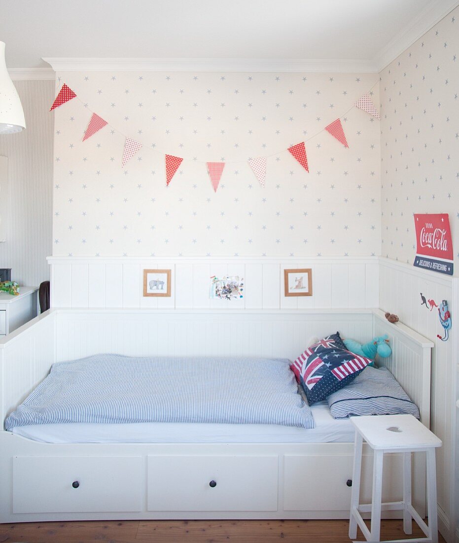 Weisses Bett mit Bettschubladen und blau-weisser Bettwäsche in Jungenzimmer mit skandinavischem Flair