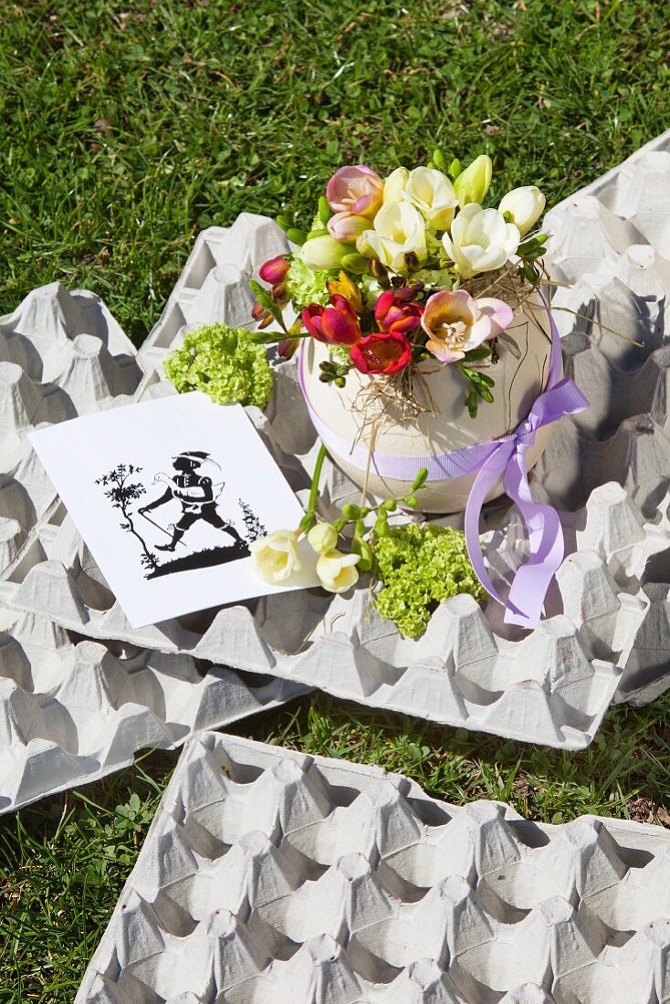 Flowers in ostrich egg on egg boxes on lawn