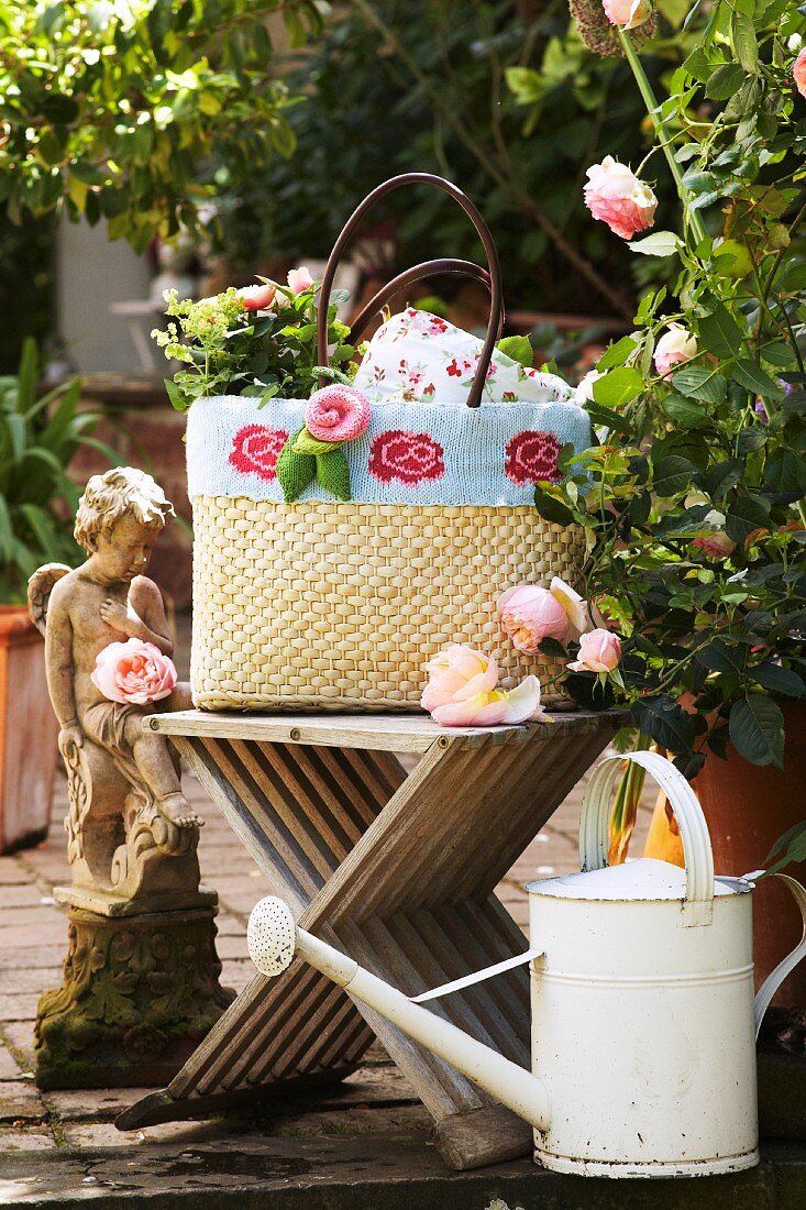 Raffia shopping bag decorated with knitted trim and knitted roses on garden terrace with vintage accessories