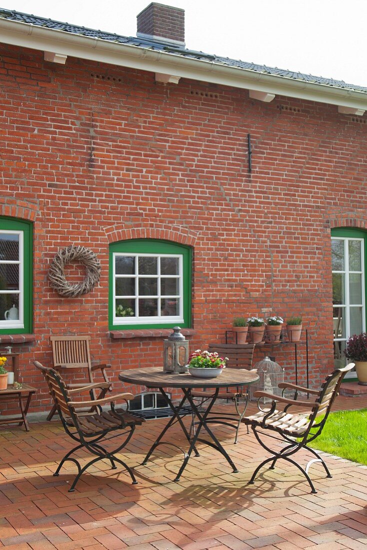 Summery terrace outside renovated brick house with white lattice windows in green frames