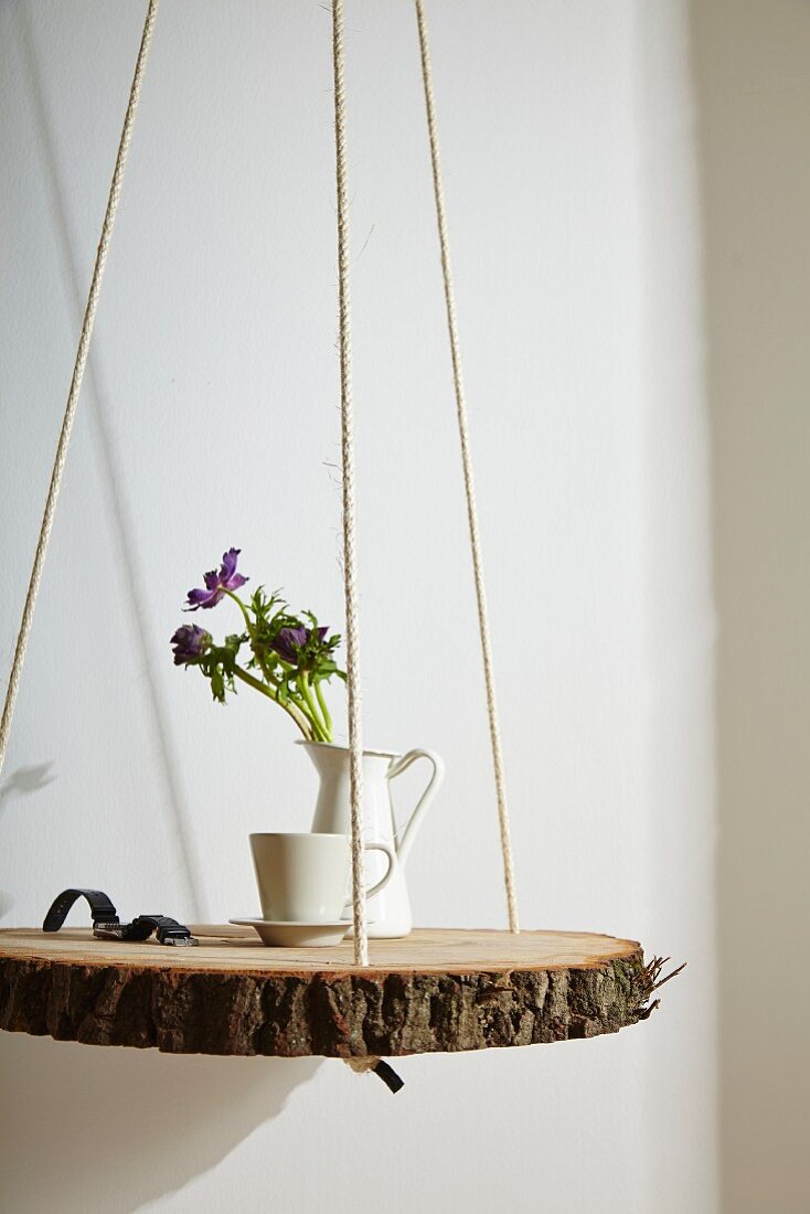 Slice of tree trunk hung from ropes and used as bedside table