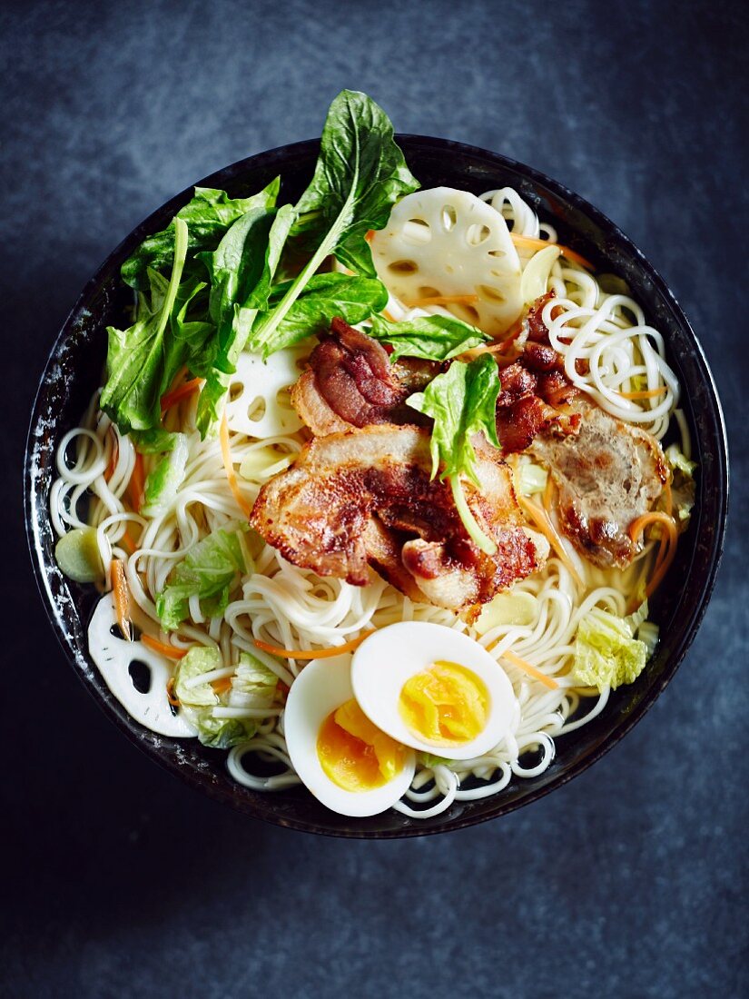 Eiernudelsuppe mit Schweinebauch, gekochtem Ei, Spinat, Lotuswurzel und Karotten (Asien)