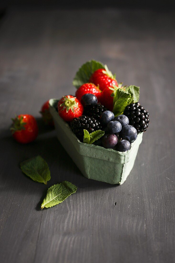 Various berries with mint in an old-fashioned cardboard punnet