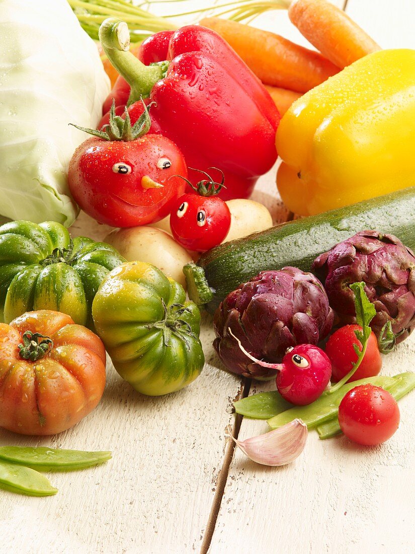 Gemüsestillleben mit Sommergemüse und Tomatengesicht