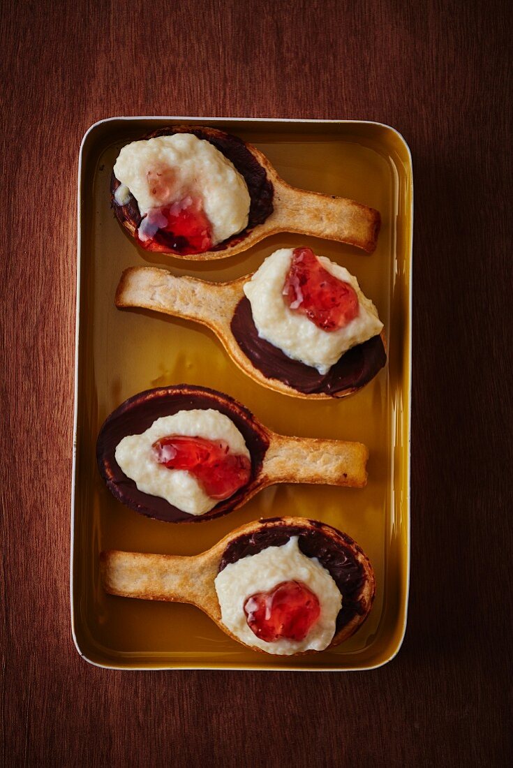 Biscuit spoons with chocolate cream, vanilla cream and redcurrant jelly