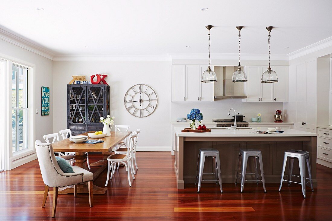 Open living room with dining area and kitchen, retro bar stools in front of kitchen counter under pendant lights