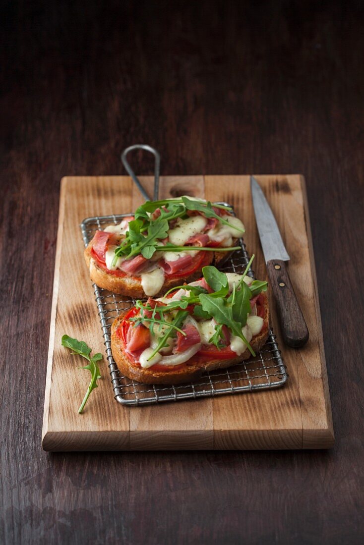 Bruschetta mit Parmaschinken, Mozzarella, Tomaten, Oliven und Rucola