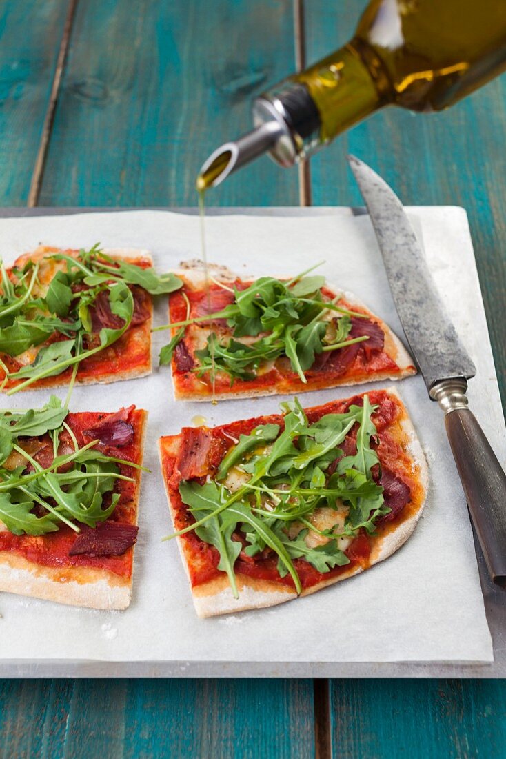 Pizza with rockets, ham, tomatoes and olive oil