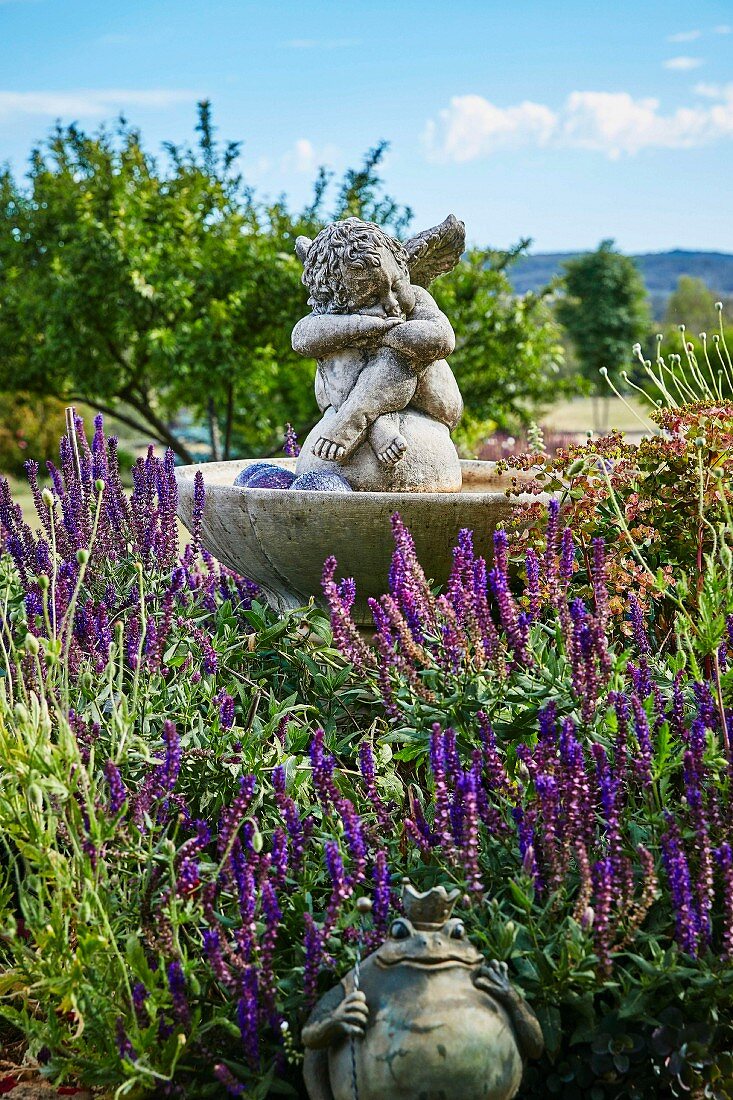 Engelfigur im Brunnen und Froschkönig im Lavendelbeet