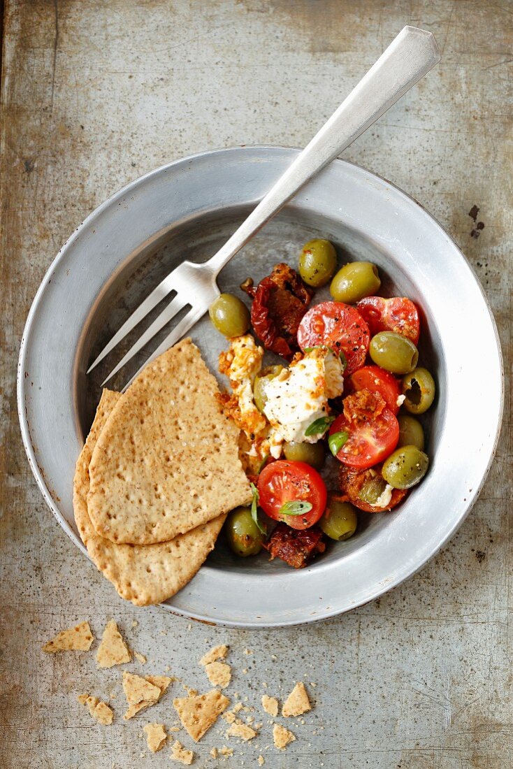 Tomato salad with dried and fresh tomatoes, olives and crispy unleavened bread
