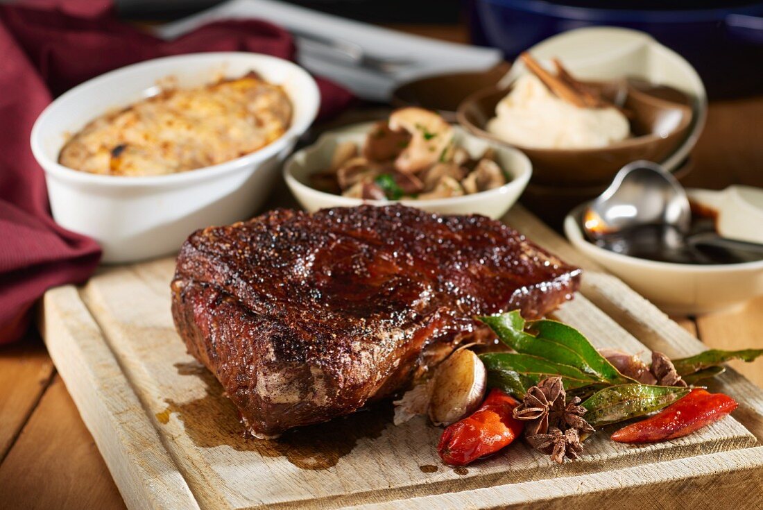 Juicy roasted tri-tip on a chopping board with side dishes