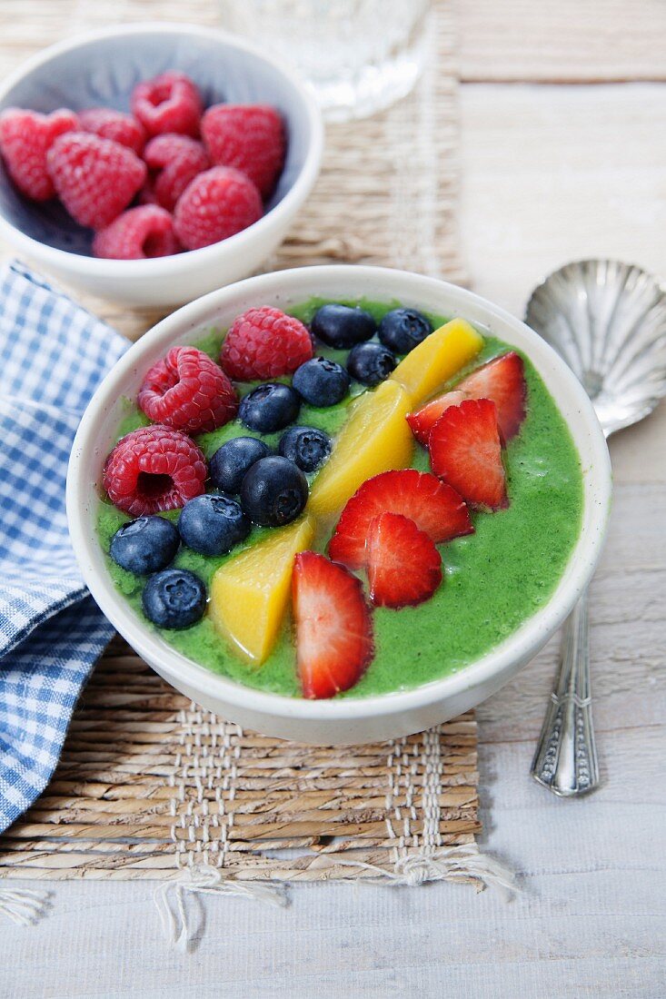 A smoothie bowl with kiwi, mango, spirulina, raspberries, blueberries and strawberries