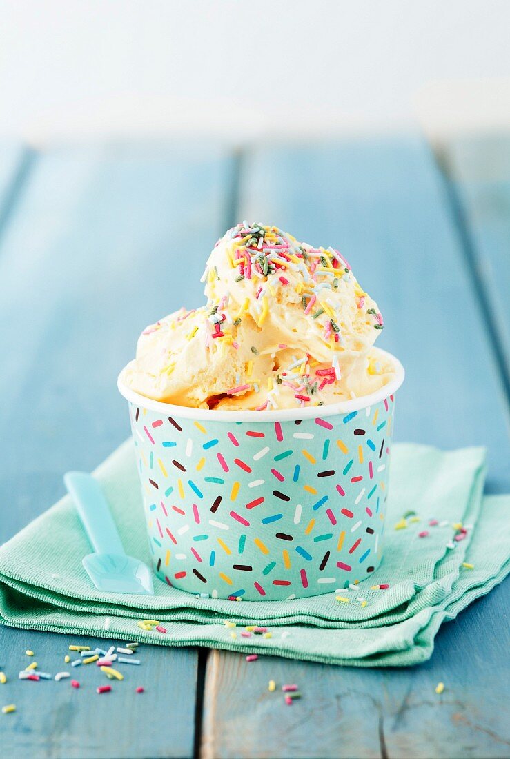 Vanilla ice cream with colourful sugar sprinkled in a paper tub