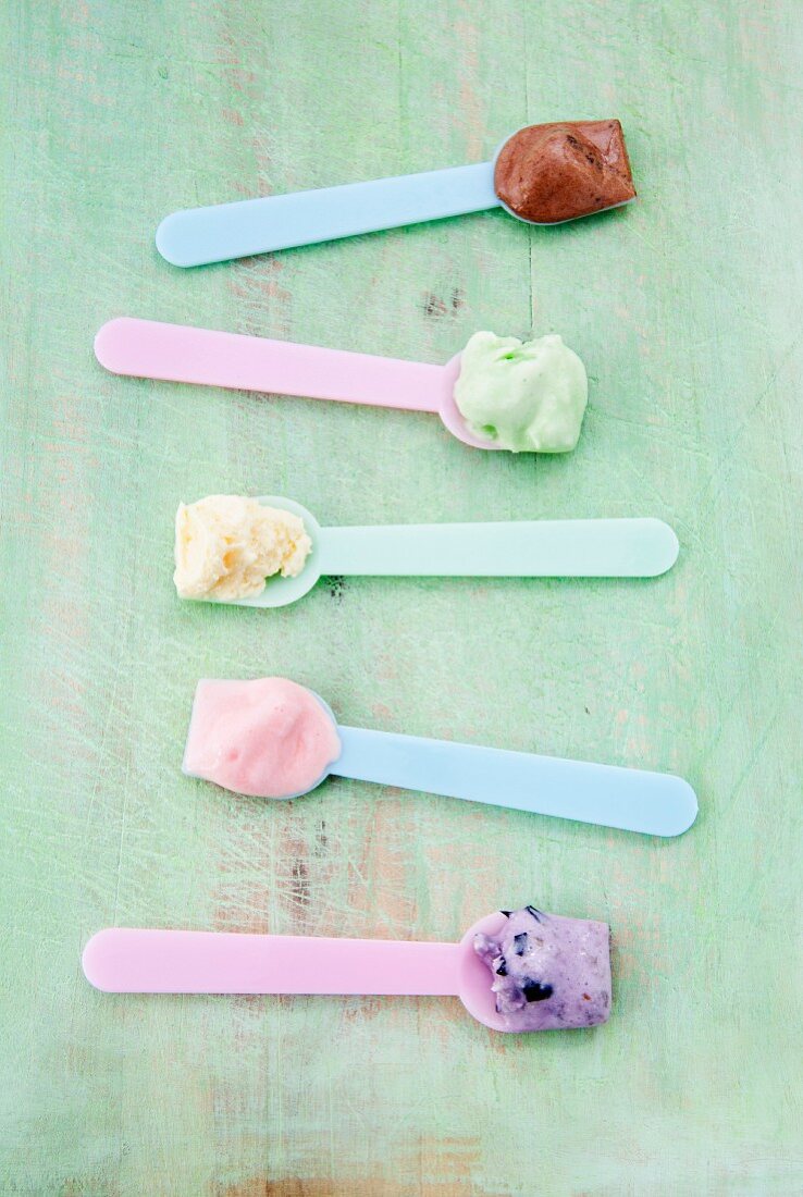 Eislöffel mit verschiedenen Eissorten: Vanille, Erdbeere, Schokolade, Heidelbeere und Minze