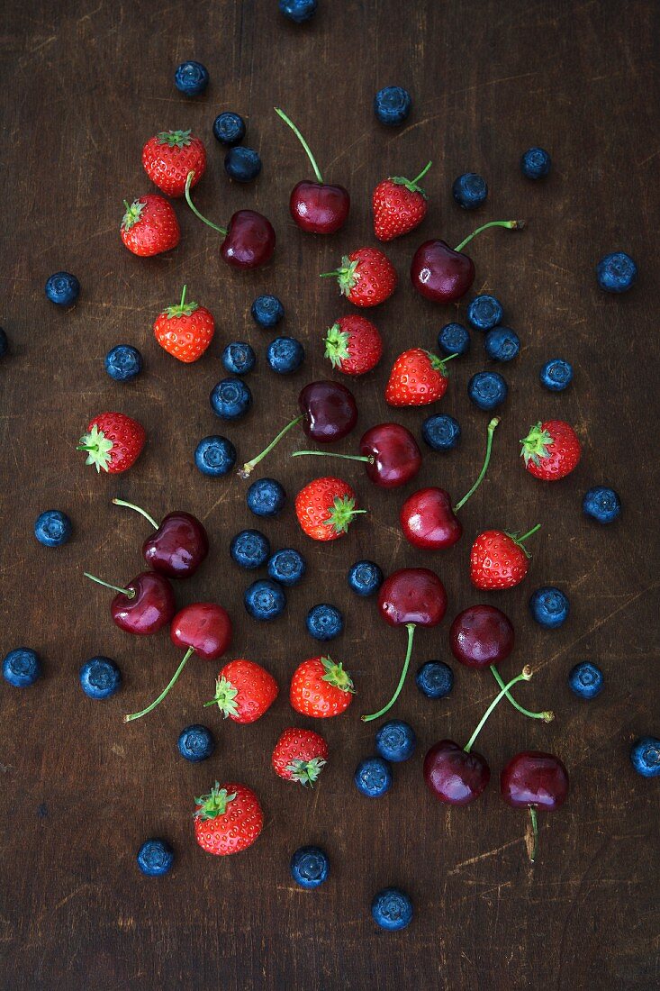 Summer fruits on a wooded board (strawberries, blueberries and cherries)