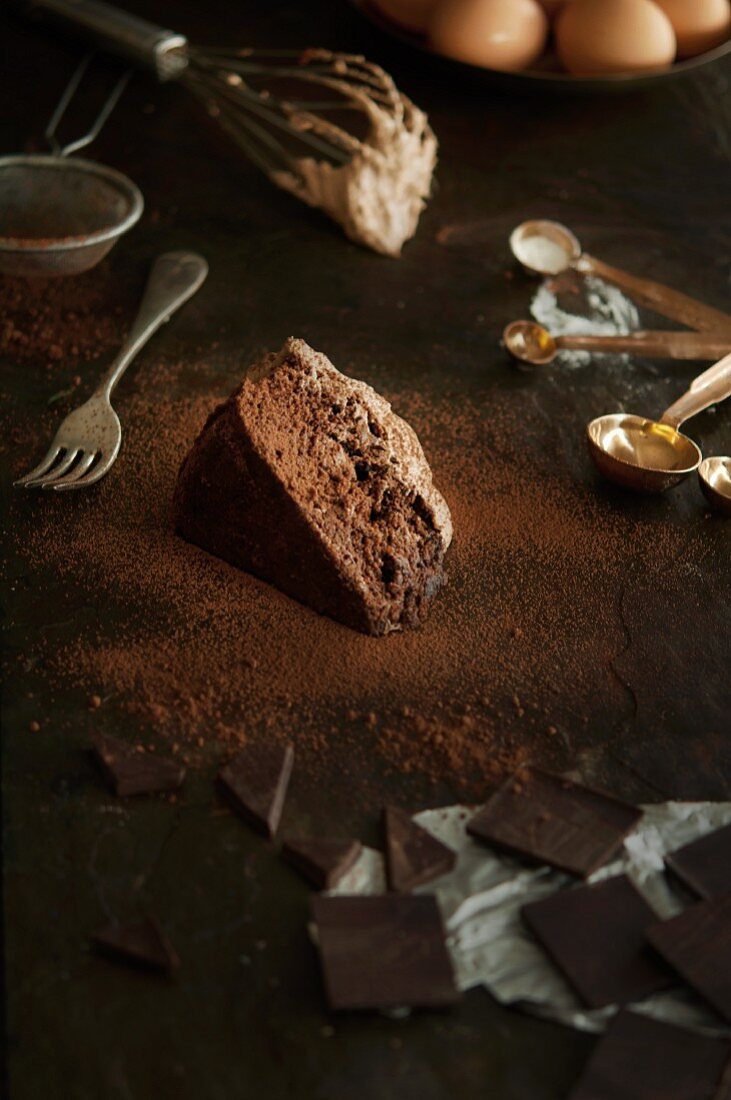 A slice of chocolate cake, baking ingredients and utensils