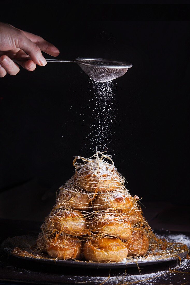 Croquembouche mit Puderzucker bestreuen