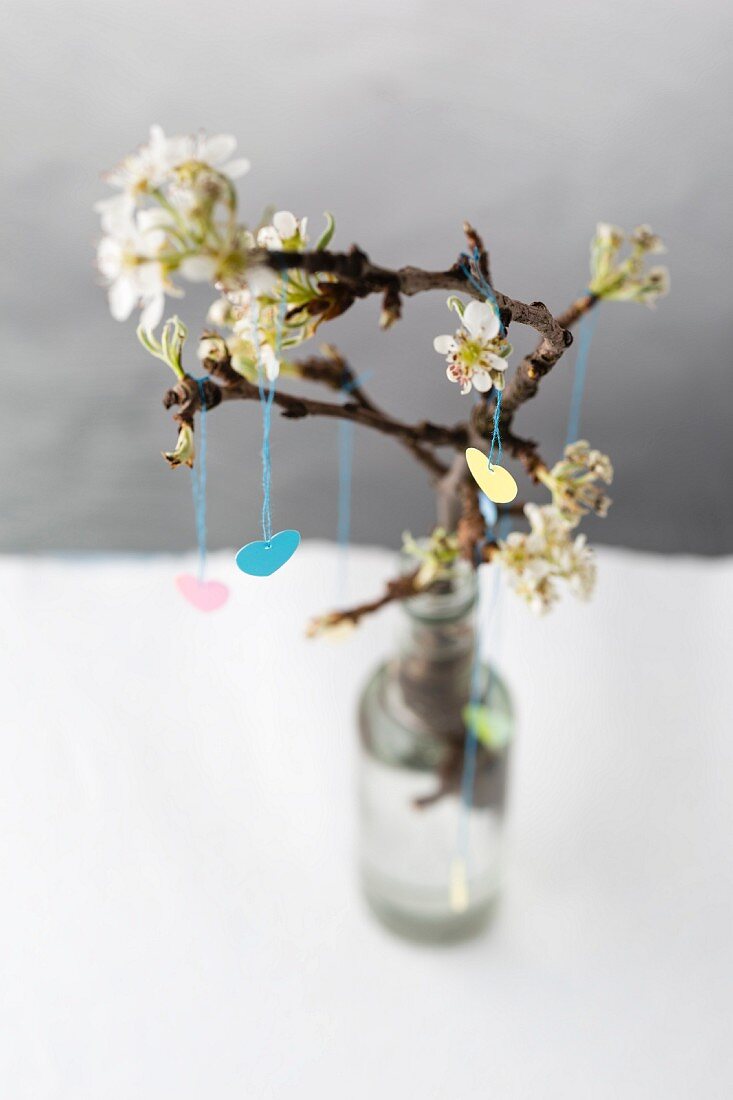 Spring arrangement: paper hearts hung from branch of blossom