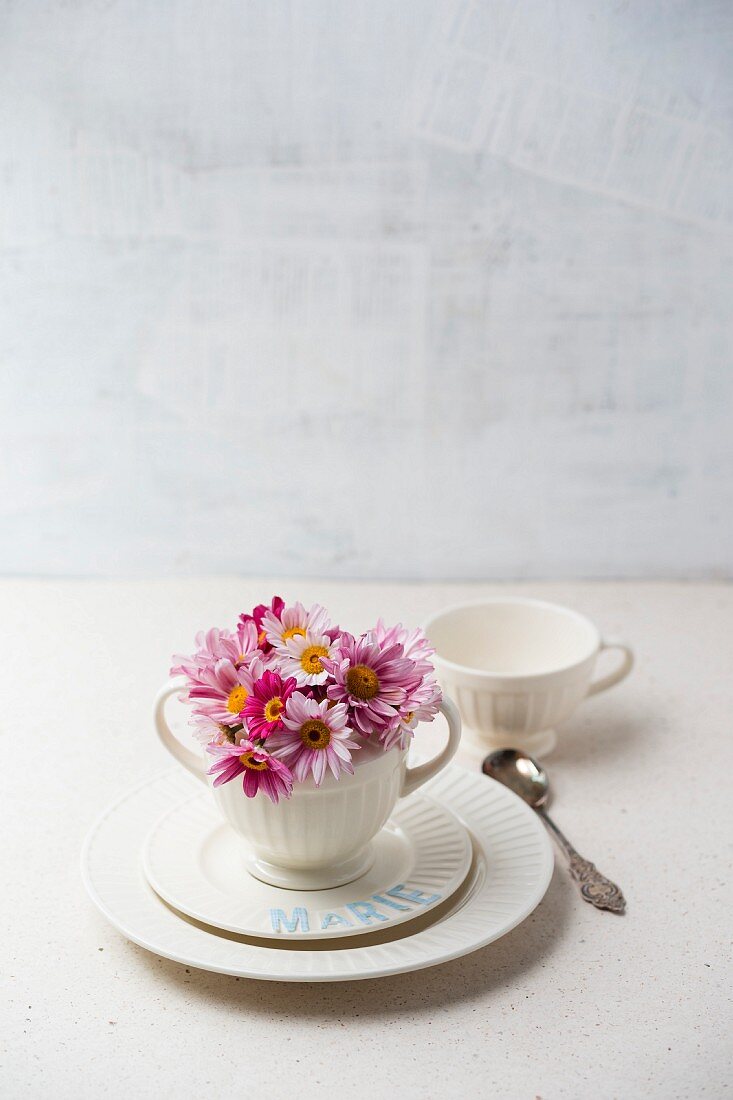 Weisses Tischgedeck dekoriert mit Blüten und Namenszug