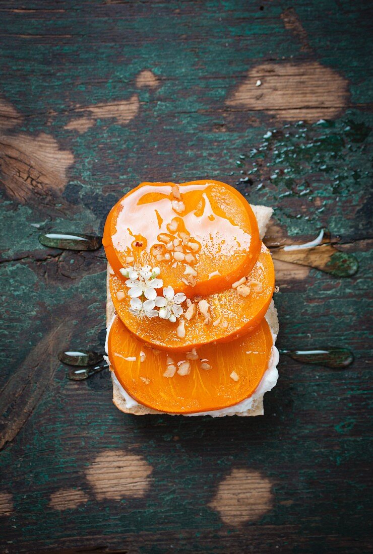 A slice of bread topped with quark, persimmons, hazelnuts and agave syrup