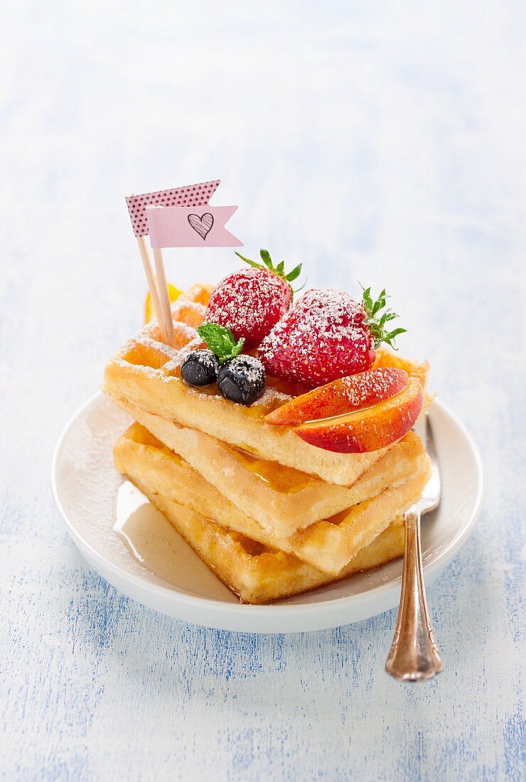 A stack of waffles with fresh fruit and agave syrup