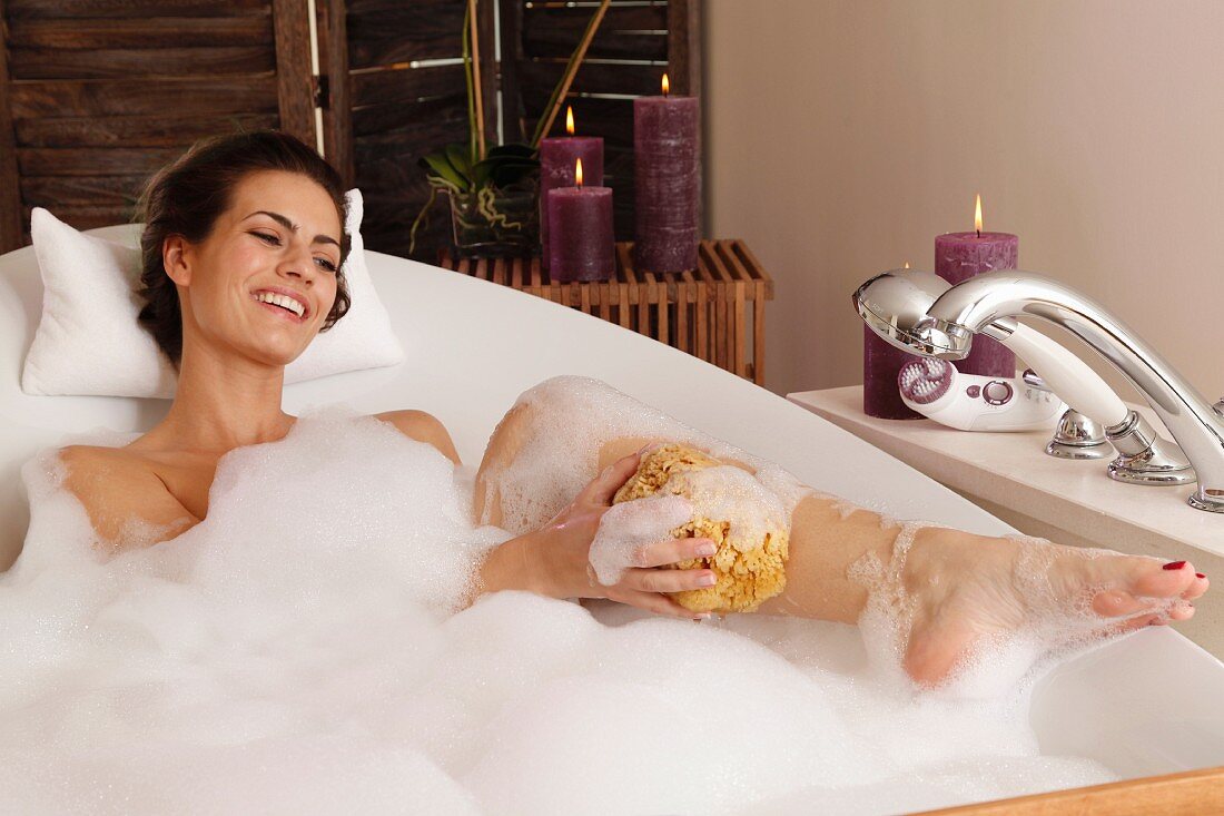 A young brunette woman taking a bath by candlelight