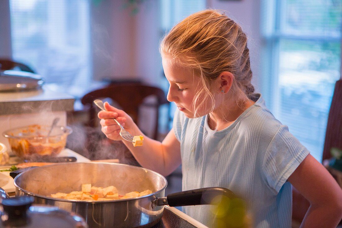 Blondes Mädchen probiert Essen beim Kochen