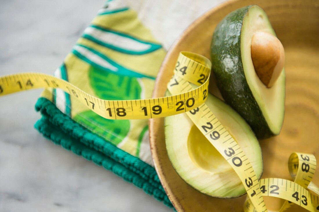 Sliced avocado in a wooden dish with a measuring tape