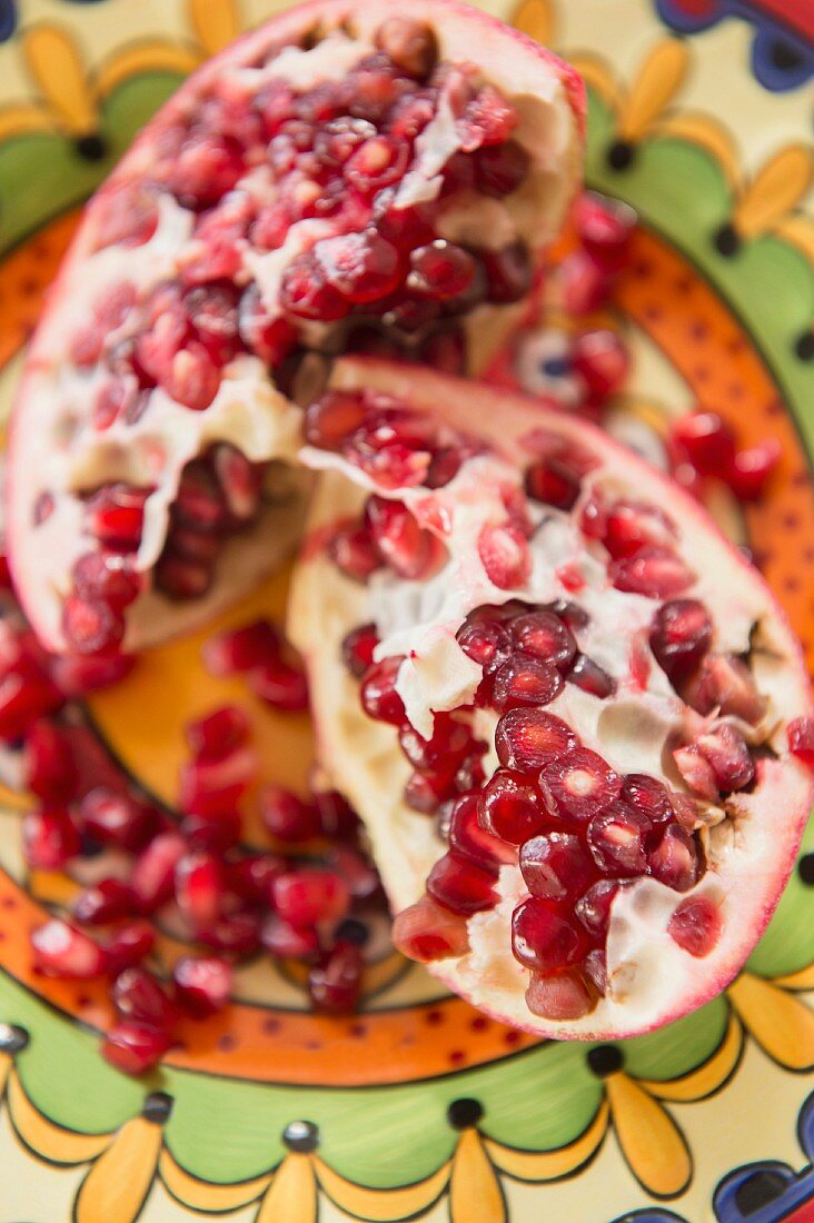 A sliced pomegranate on a colourful plate