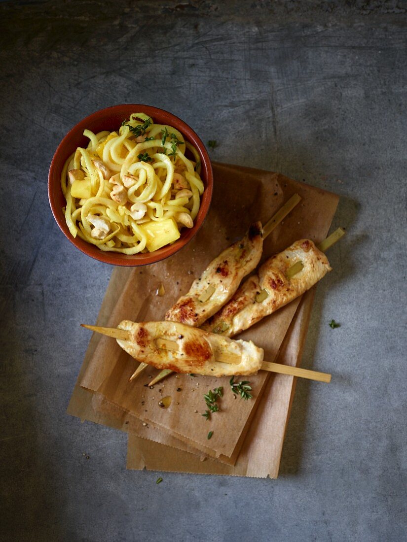 Chicken skewers and a celery spiral salad with pineapple, curry and cashew nuts