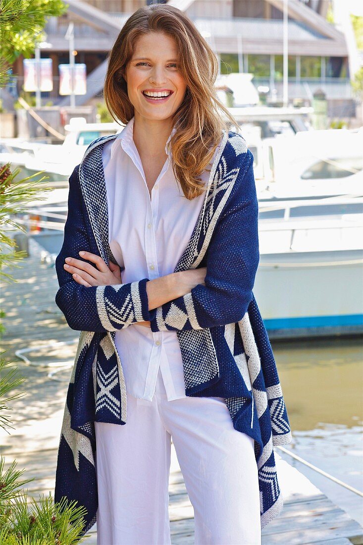 A young brunette woman wearing a white blouse and a blue-and-white cardigan