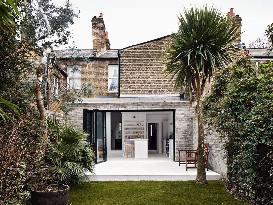 Traditional brick house with extension seen from garden with yucca palm tree