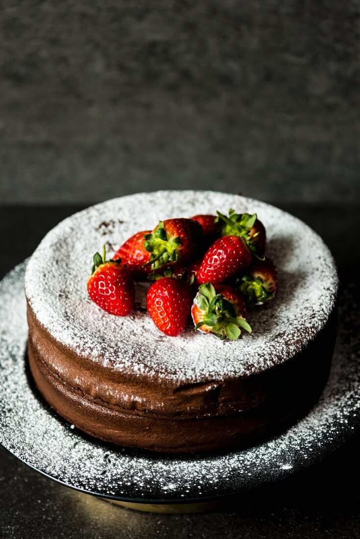 Chocolate cake with icing sugar and strawberries