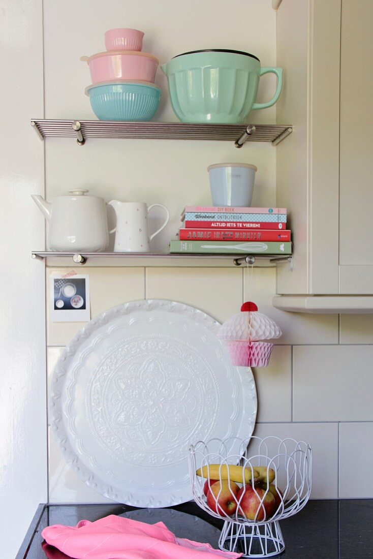 Stacked books and retro crockery on wall-mounted kitchen shelves
