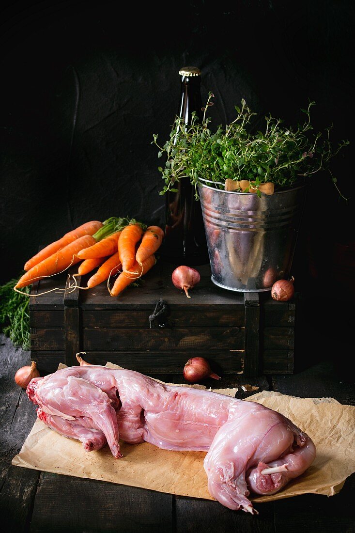 Raw hare on a piece of paper with ingredients on a small wooden crate