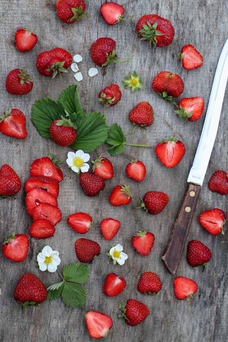 Frische Erdbeeren, ganz und halbiert auf Holzuntergrund