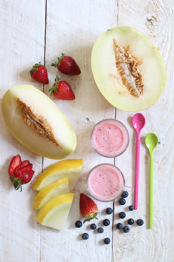 Fresh fruit and fruit yoghurt with spoons on a wooden surface