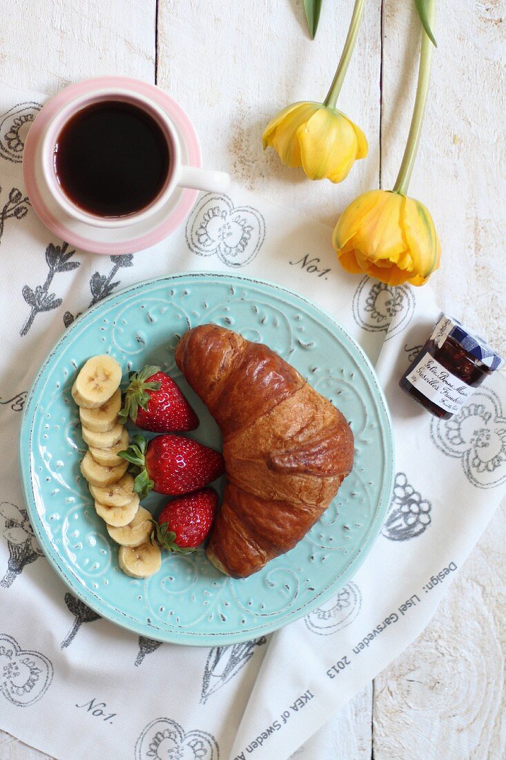 Süsses Frühstück mit Croissant, Obst, Marmelade und Kaffee