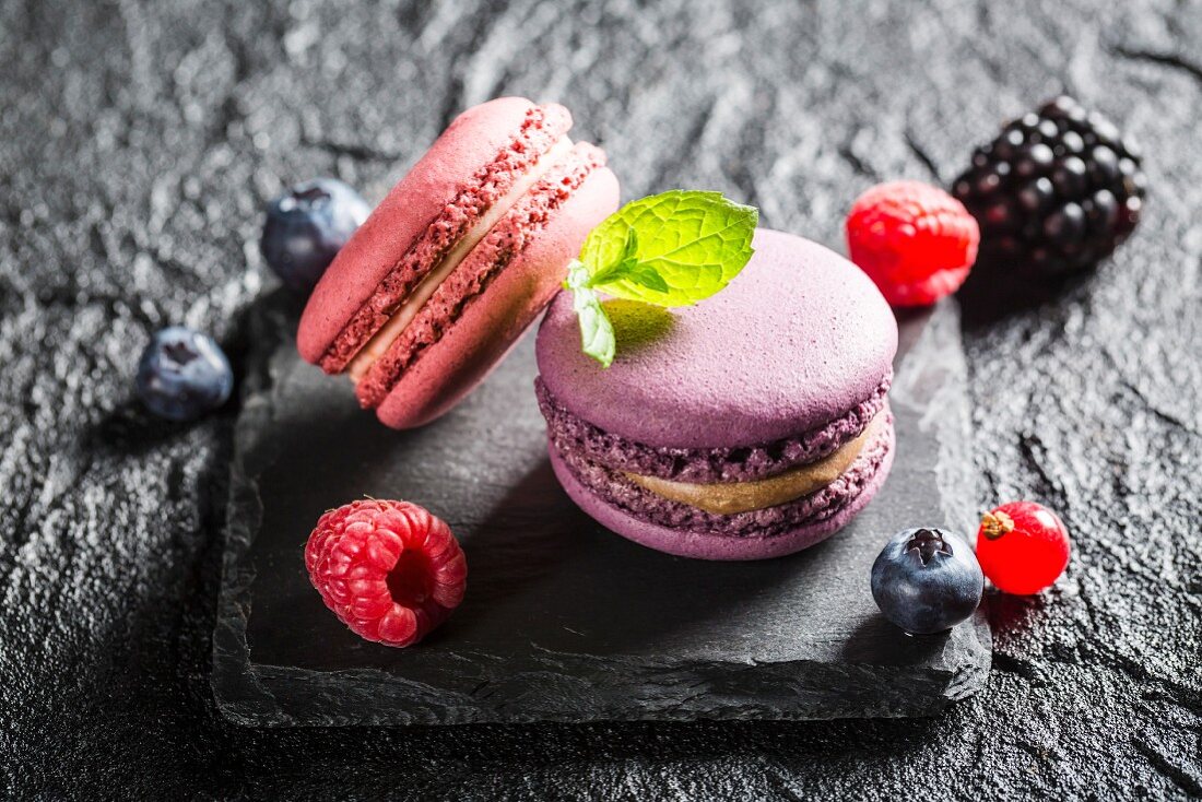 Macaroons with various berries on a black stone