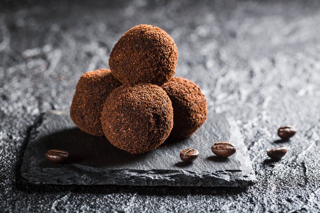Trüffelpralinen mit Kaffeebohnen auf schwarzem Stein