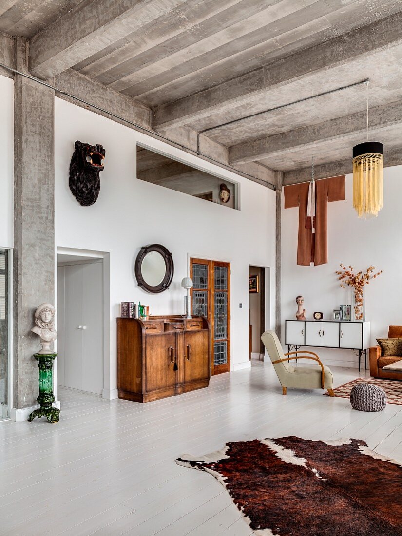 Ribbed concrete ceiling and white wooden floor in open-plan eclectic living area