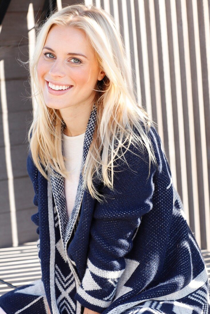 A young blonde woman wearing a top and a blue-and-white cardigan