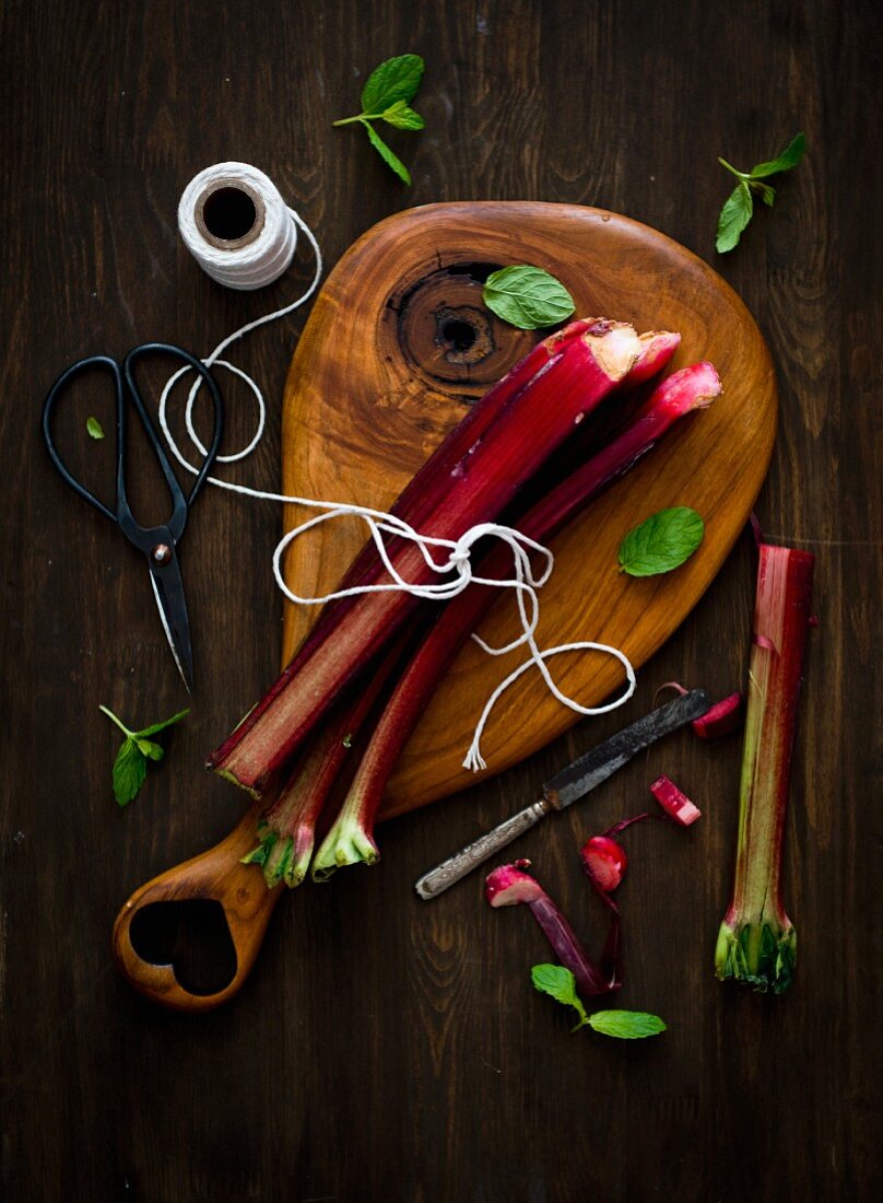 Rhubarb stalks and pieces on a wooden board with kitchen twine