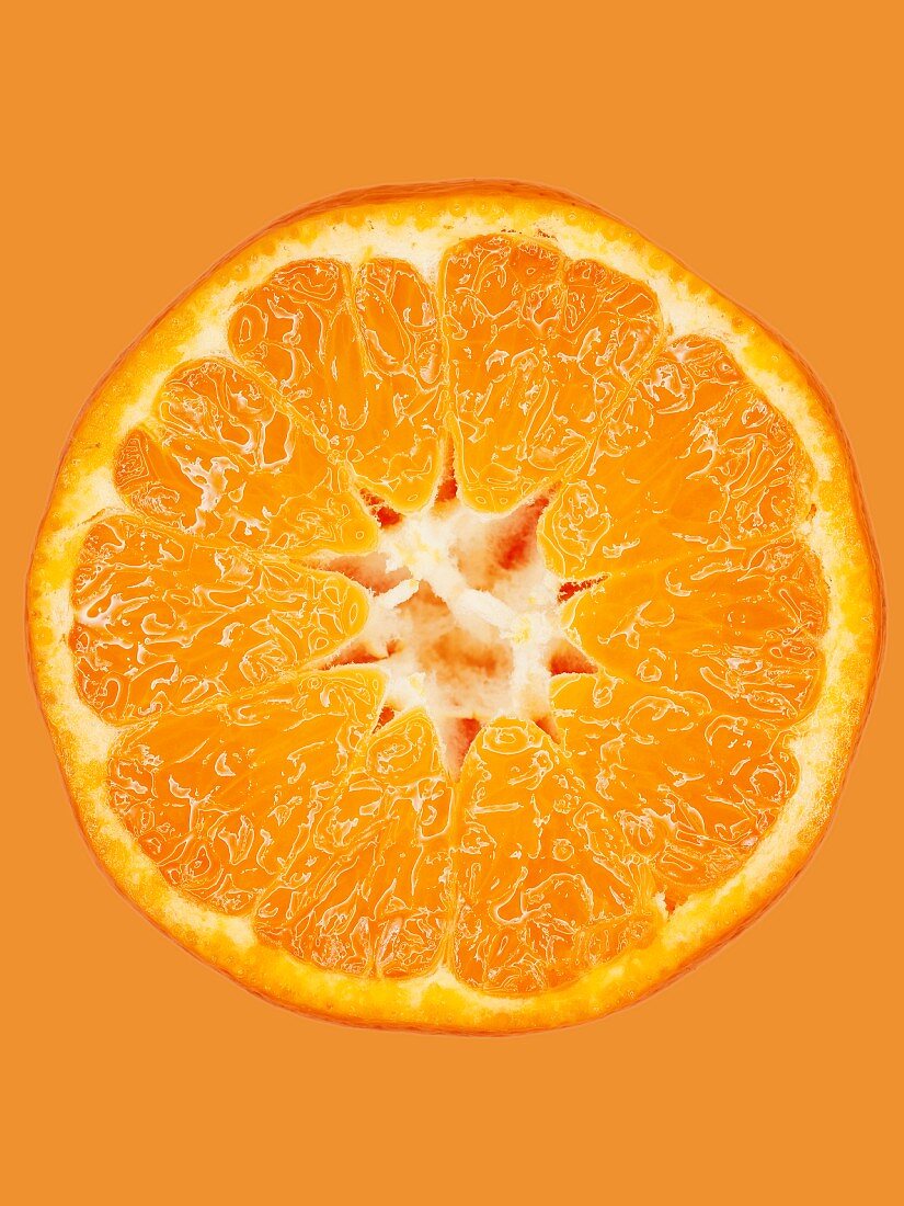 Aufgeschnittene Mandarine vor orangem Hintergrund, Close-Up