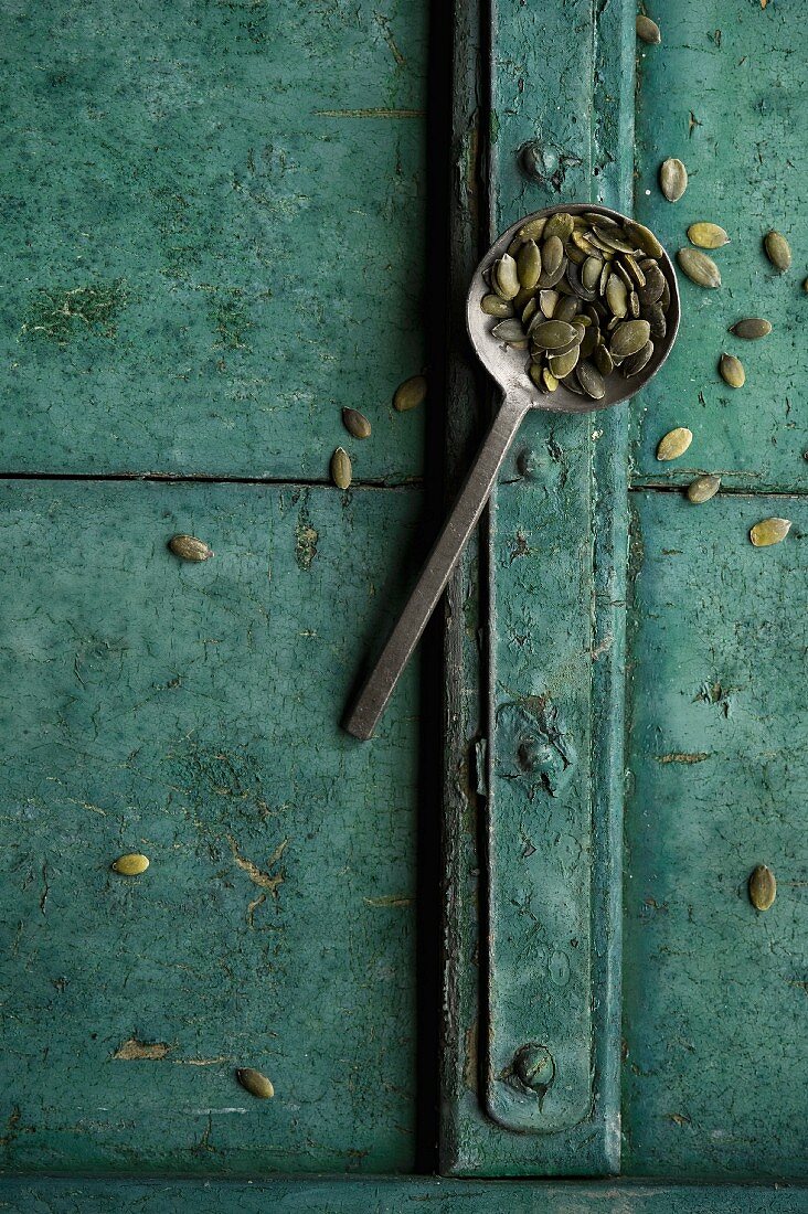 Pumpkin seeds on a spoon on a rustic surface