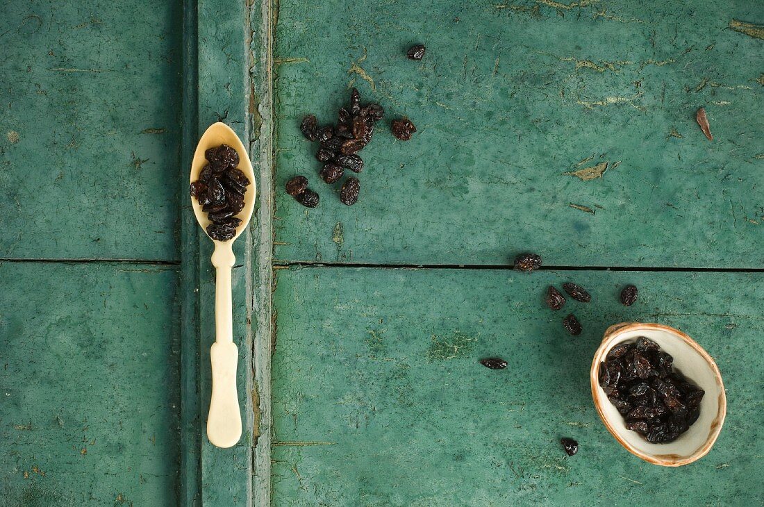 Dried cranberries on a spoon and in a bowl on a rustic surface