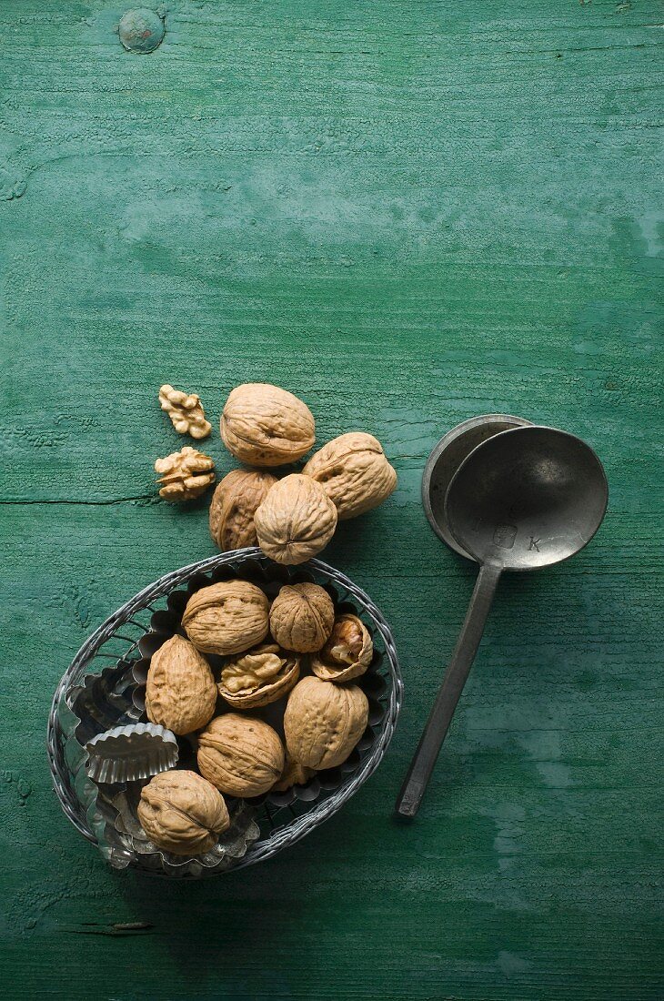 Walnuts, shelled and unshelled, in a bowl on a rustic wooden surface next to a spoon
