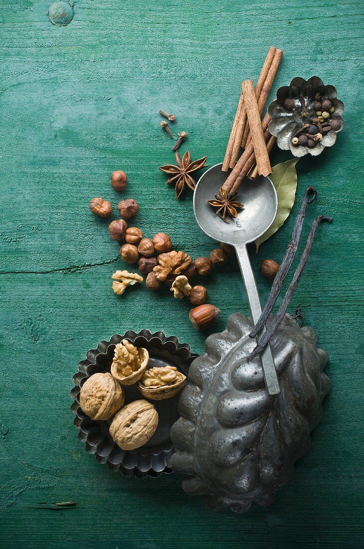 Various Christmas spices and nuts in baking tins on a rustic wooden surface