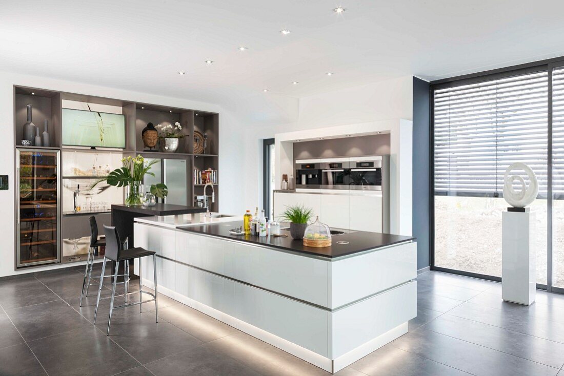 A white kitchen island with base lighting in an open-plan designer kitchen