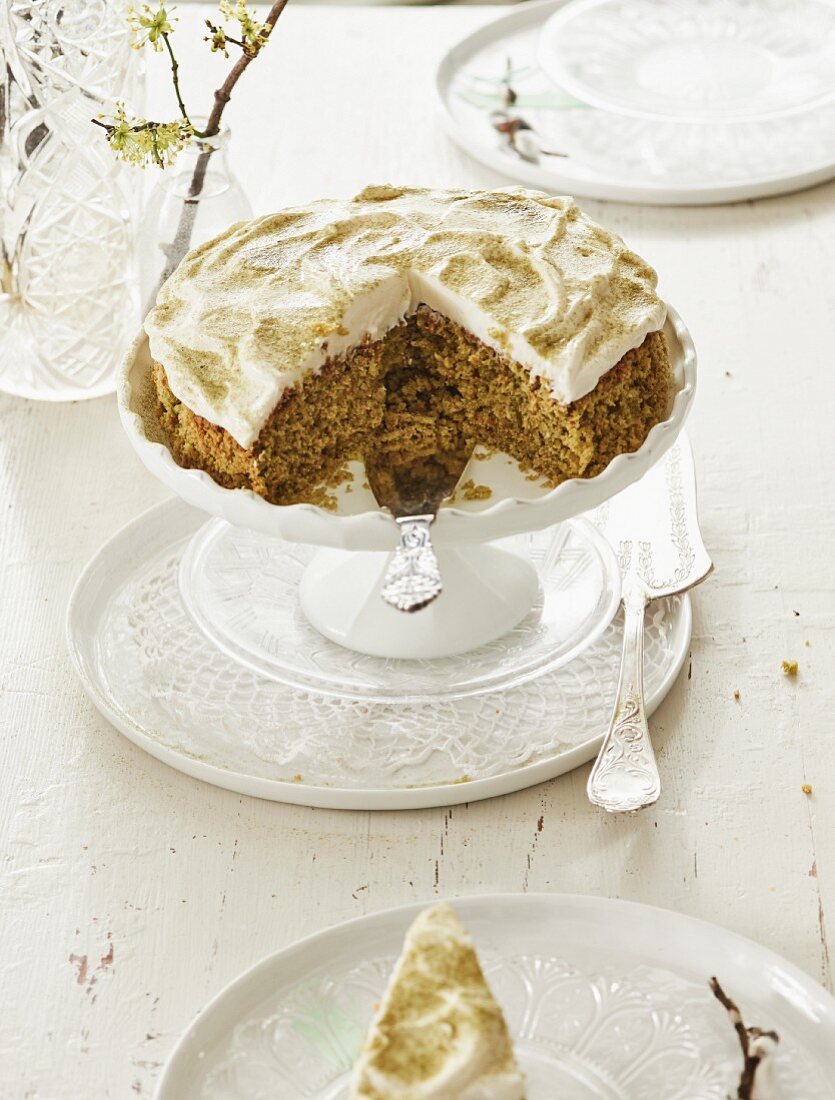 A slice cut out of a coconut and carrot cake with cream cheese topping